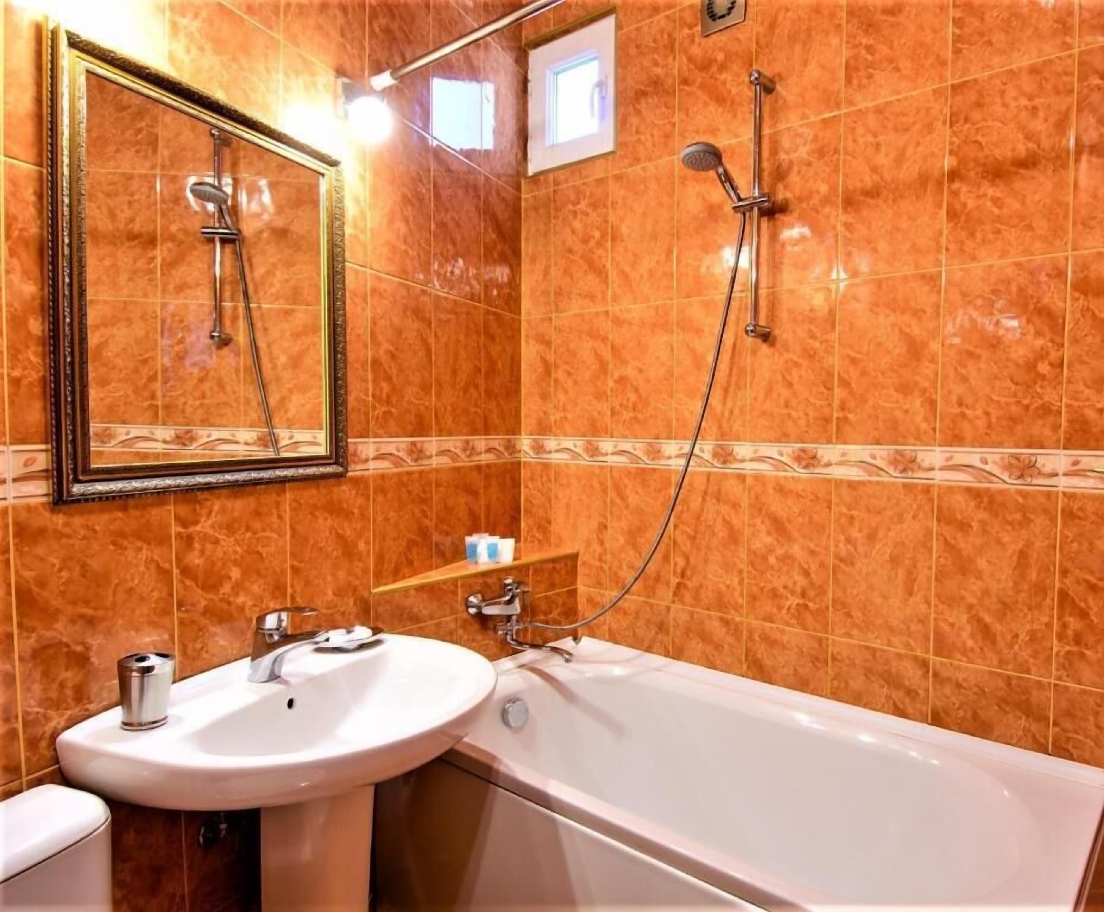 A bathroom with a white bathtub, a sink, and a shower with a handheld showerhead.