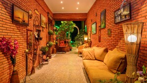 Un espacio interior acogedor con pared de ladrillo, un sofá y diversas plantas y adornos.