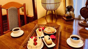 Una mesa de comedor con una bandeja de postres, tazas de café y una lámpara decorativa.
