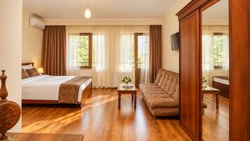 Une chambre d’hôtel avec un lit, un canapé, une petite table et un miroir.