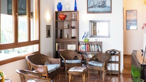 Un amplio espacio de sala con muebles de mimbre, un ventilador de techo y una estantería.