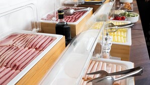 Un bufé con diversos alimentos, incluyendo carnes, quesos y verduras.