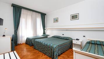 Una camera d'albergo con due letti, una scrivania, una sedia e una televisione.