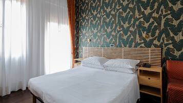 A neatly made bed with white linens, a wooden headboard, and a bedside table with a lamp.