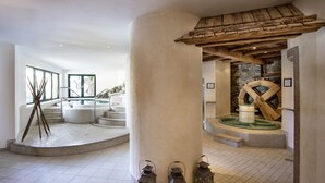 A spa area with a hot tub, stone wall, and wooden beams. - Hotel Elisabeth (Kirchberg in Tirol)