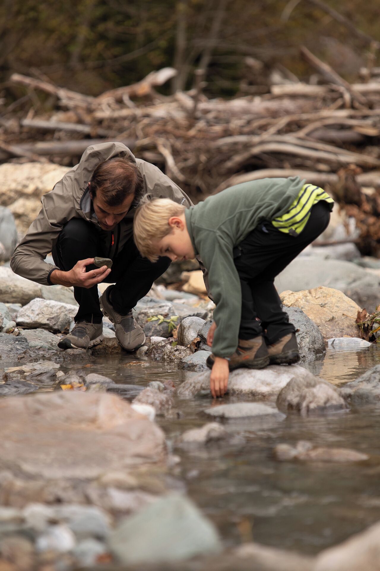 Two people examining rocks by a stream.