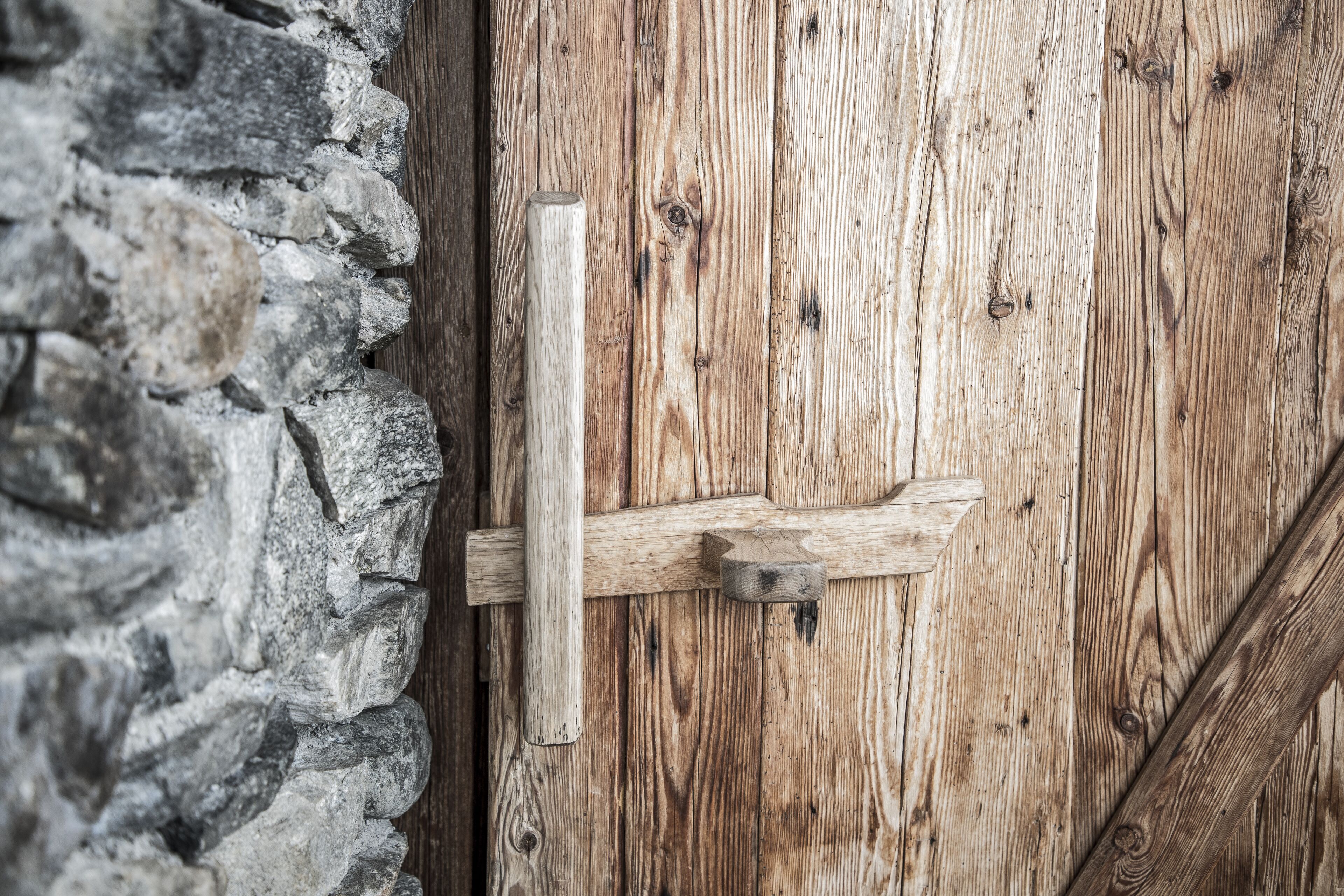 A wooden door with a metal latch and a stone wall.