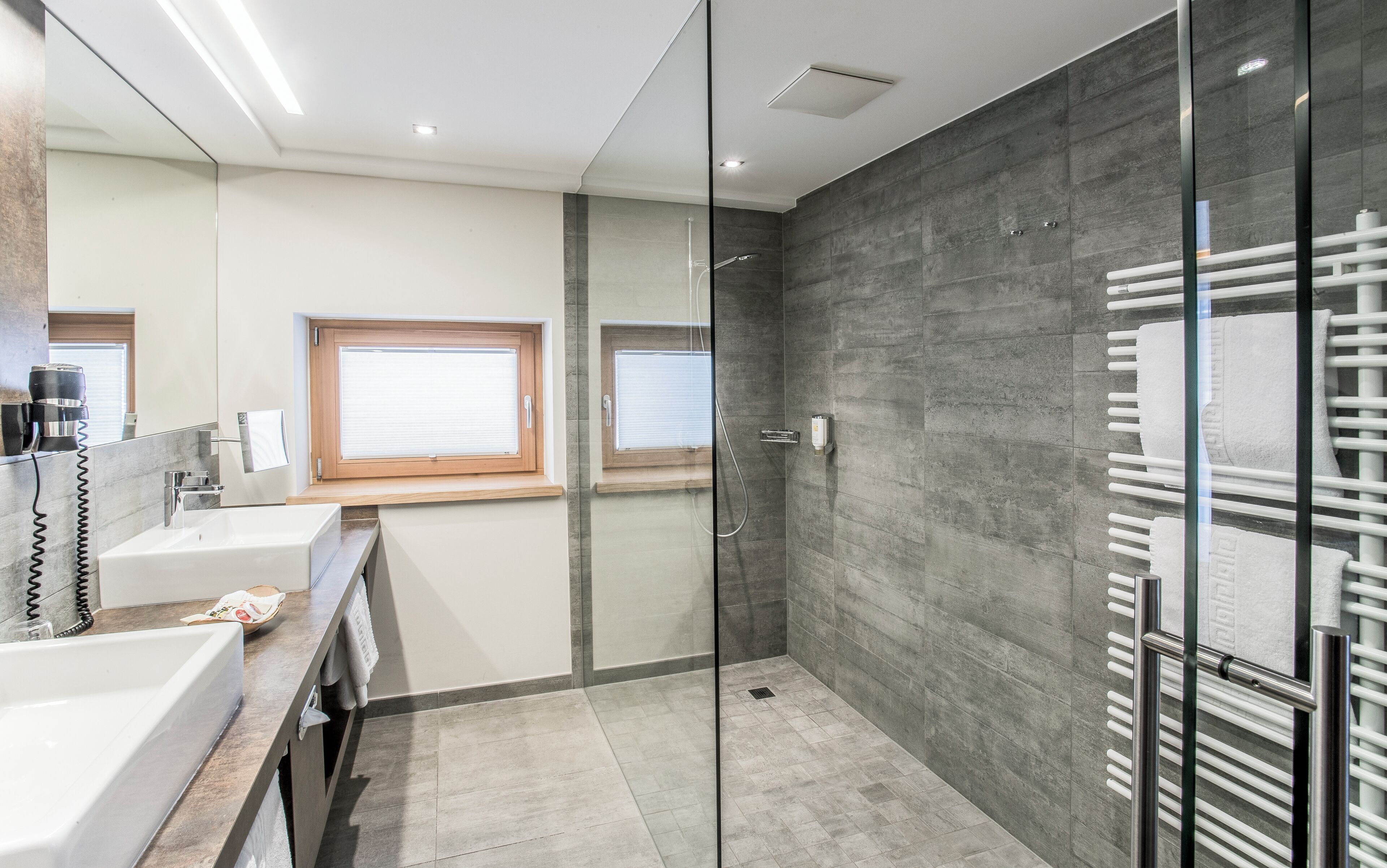 A modern bathroom with a glass shower enclosure, a vanity with a sink, and a towel rack.