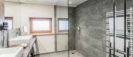 A modern bathroom with a glass shower enclosure, a vanity with a sink, and a towel rack.