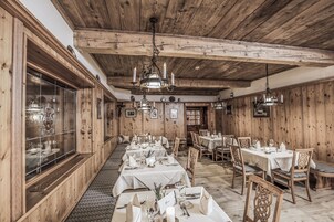 Un restaurante con paredes y techo de madera, mesas dispuestas con manteles blancos y candelabros.