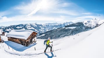 Une cabane en bois, dont le toit est recouvert de neige, nichée au cœur d’un paysage montagneux enneigé.