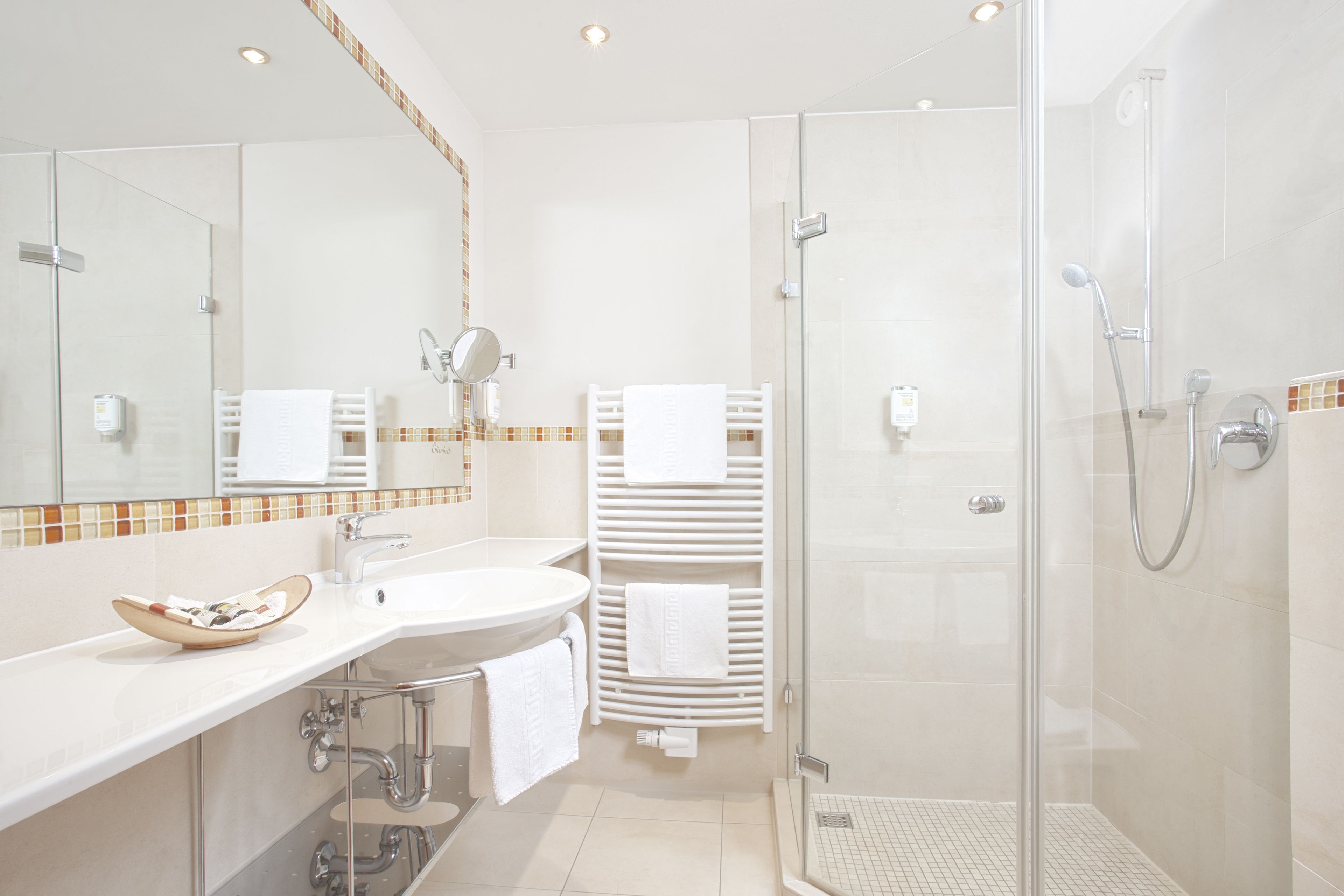 A modern bathroom with a glass shower enclosure, a white sink, and a mirror.