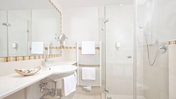 A modern bathroom with a glass shower enclosure, a white sink, and a mirror.