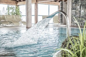 Una piscina techada, una piscina al aire libre, sombrillas