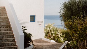 A white building with blue windows and a stone staircase leading to a door.
