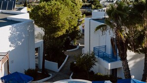 A resort with a pool area, sun loungers, and a view of the sea.