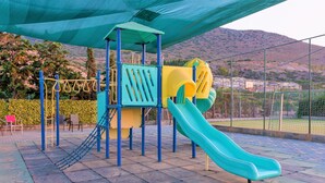 A playground with a slide, climbing structures, and a shaded area.