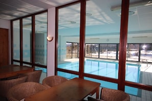 A poolside area with wicker furniture and large windows overlooking a swimming pool. - Le Hameau du Puy (Le Dévoluy)