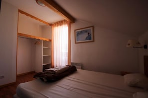 A bedroom with a bed, a wardrobe, a painting, and a lamp. - Le Hameau du Puy (Le Dévoluy)