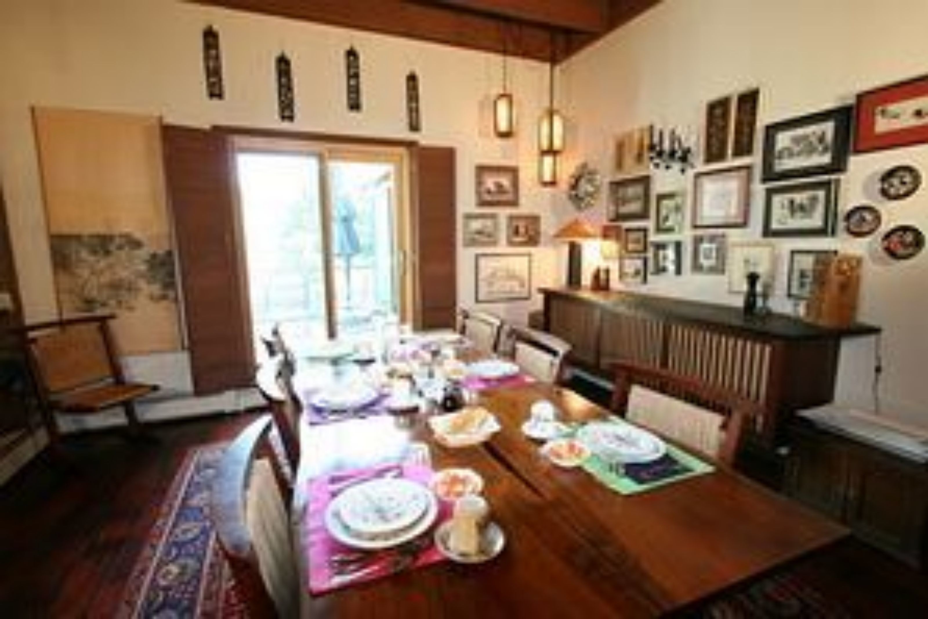 A dining area with a wooden table set for a meal, surrounded by chairs.