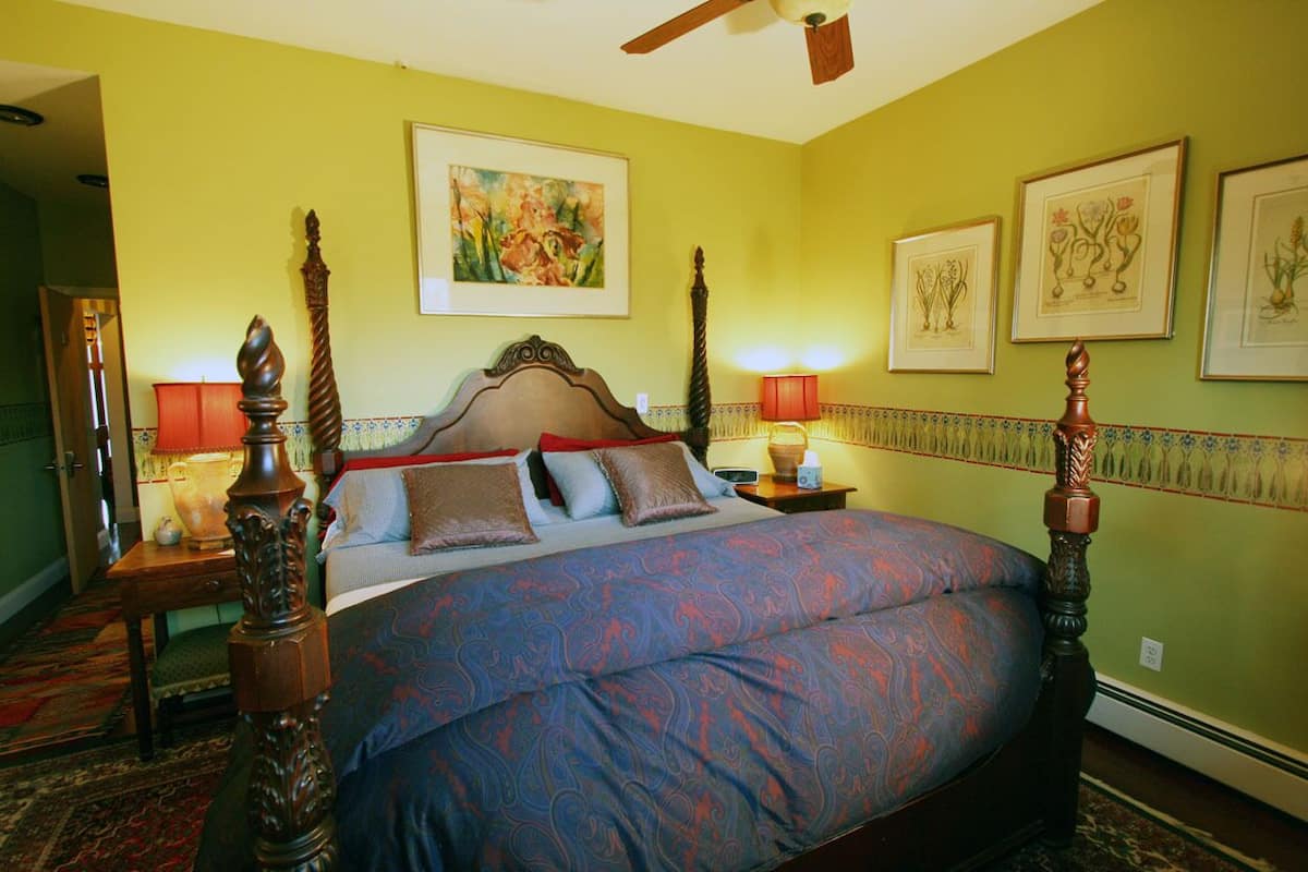 Un dormitorio con cama con dosel, ventilador de techo y obras de arte en las paredes.