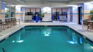 Une piscine avec des chaises longues et un petit espace salon.