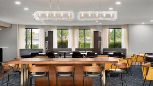 Une salle de conférence dotée d’une grande table en bois, de nombreuses chaises et d’un lustre moderne.