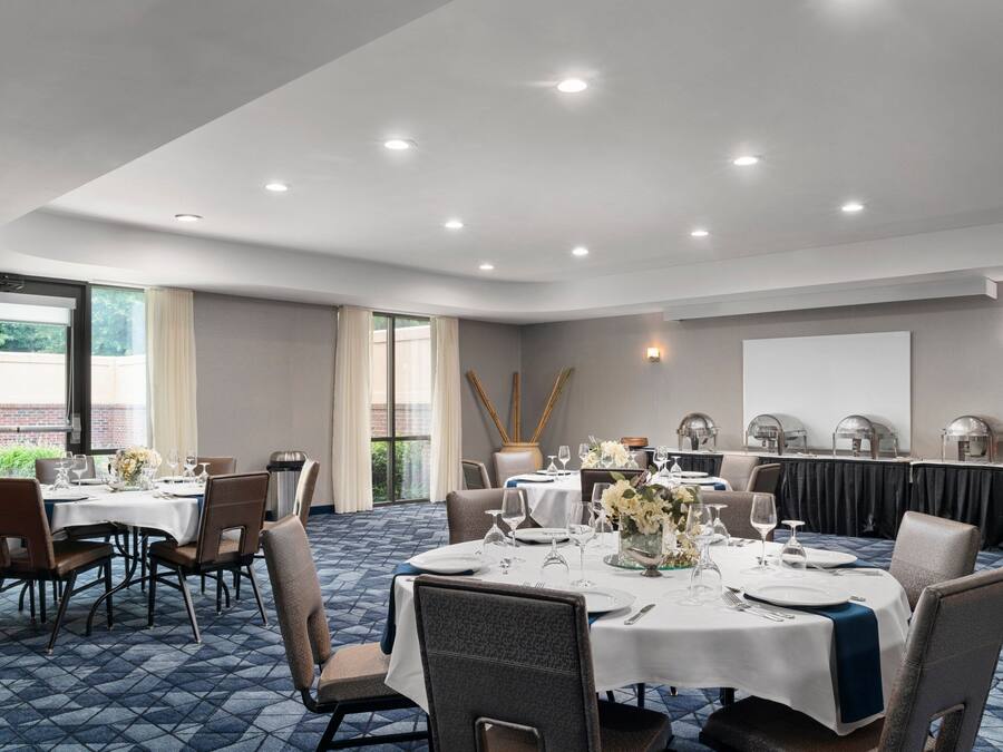 A conference room with round tables, chairs, and a projector screen.