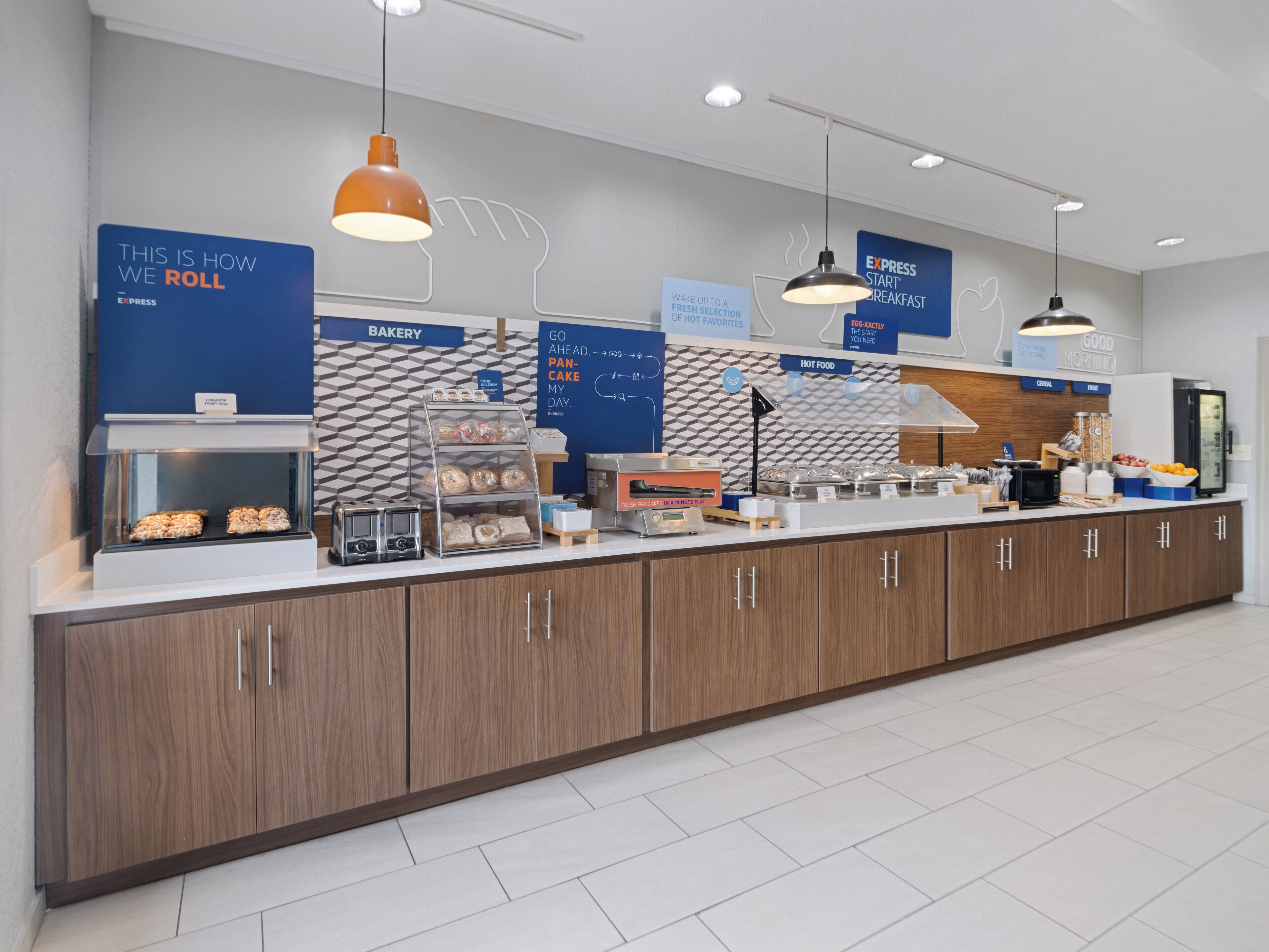 Un bar à petit-déjeuner moderne, doté d’un espace boulangerie, d’un coin café et d’un réfrigérateur rempli de boissons.