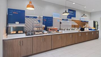 Un bar à petit-déjeuner moderne, doté d’un espace boulangerie, d’un coin café et d’un réfrigérateur rempli de boissons.