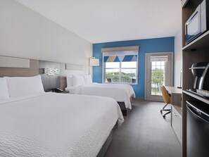 Una habitación de hotel con dos camas, un escritorio, una silla y un televisor.