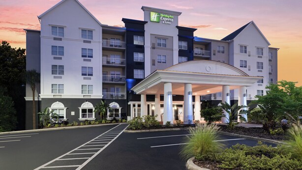 A Holiday Inn Express & Suites hotel with a central entrance, multiple floors, and a parking lot.