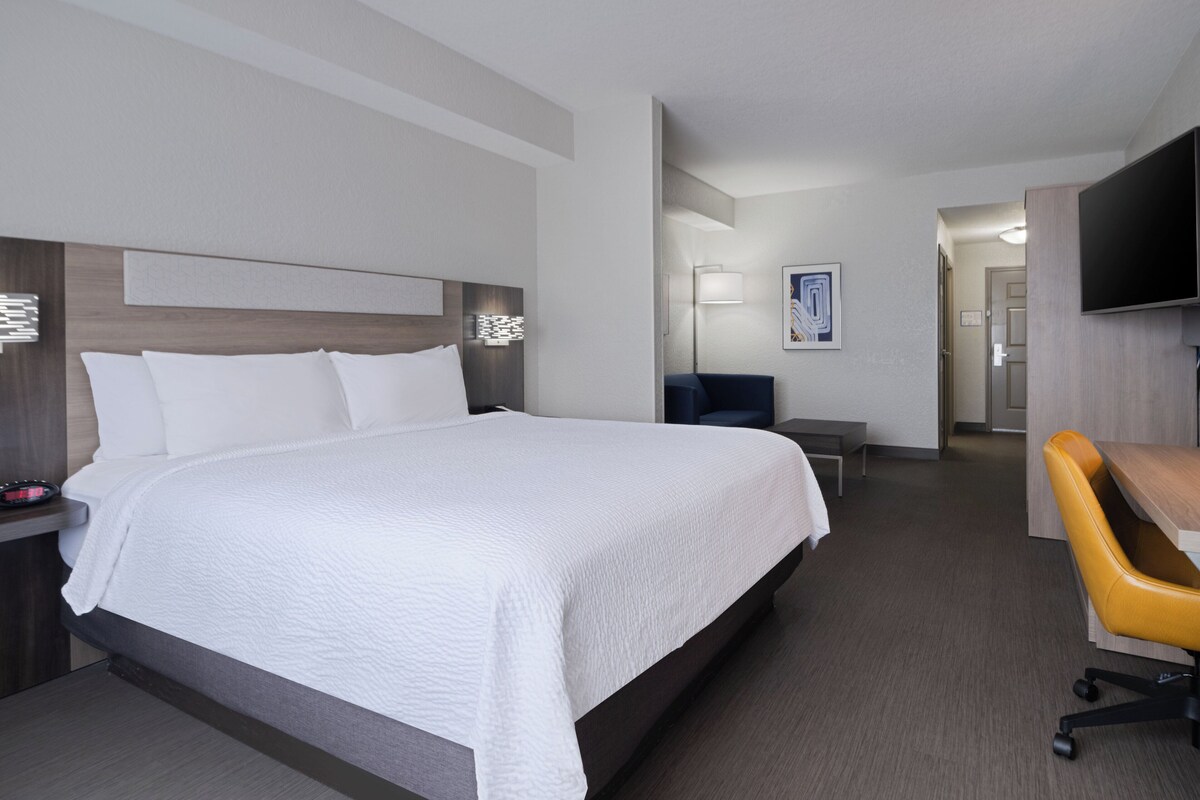 Una habitación de hotel con una cama grande, un escritorio, una silla y un televisor.