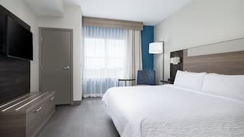 Una habitación de hotel con una cama grande, un televisor de pantalla plana, un escritorio y una silla.