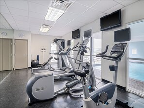 Un gimnasio con cintas de correr, elípticas y una bicicleta estática.