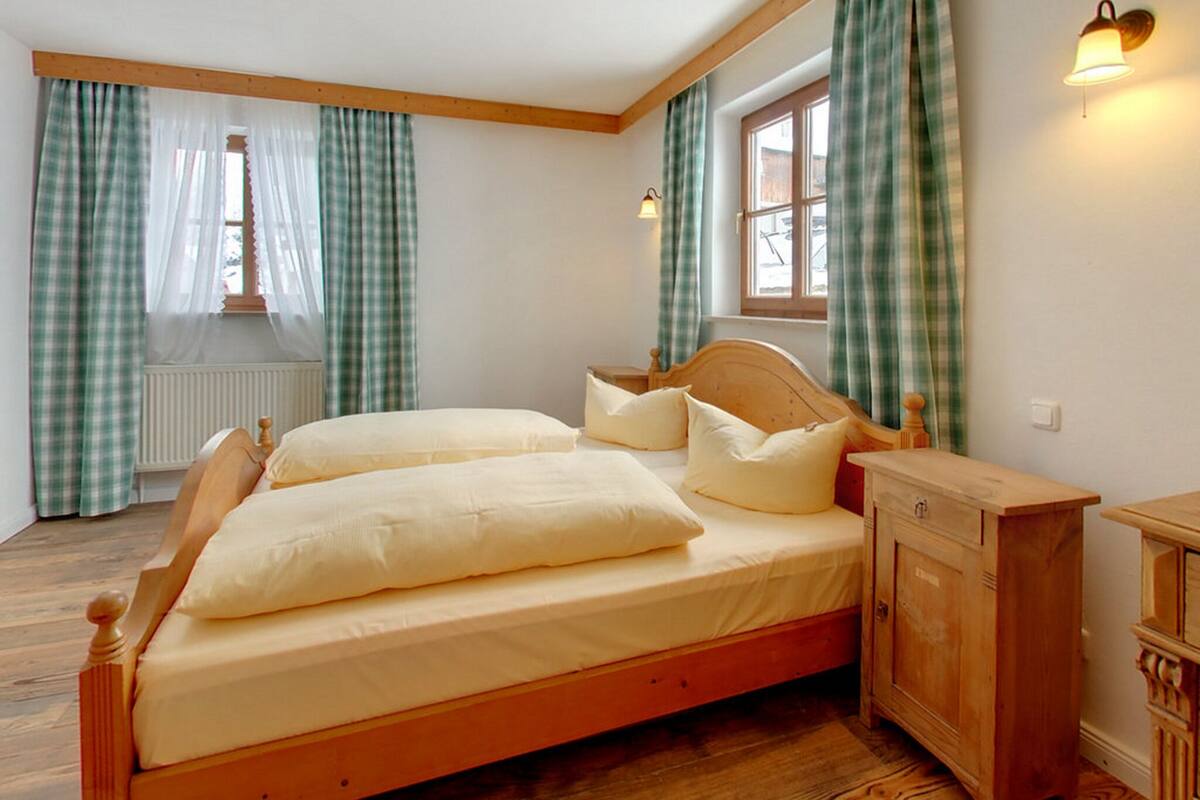 Un lit en bois avec une tête de lit, deux oreillers et une table de chevet avec une lampe.