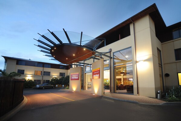 A hotel entrance with a modern glass canopy and signage for Heartland.