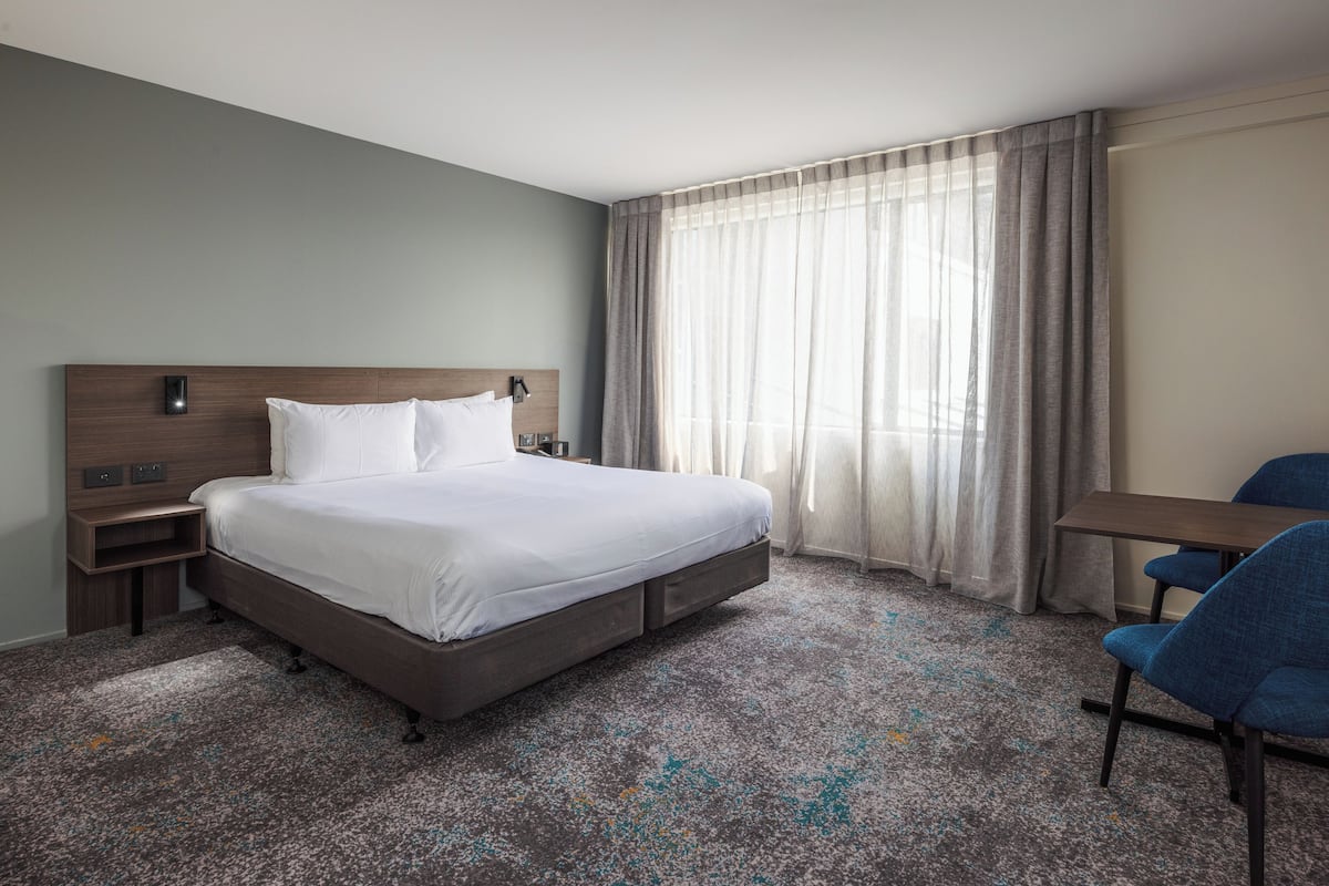 Een hotelkamer met een groot bed, een bureau en een stoel.