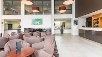 A modern lobby with striped sofas, a wooden reception desk, and a TV mounted on the wall.