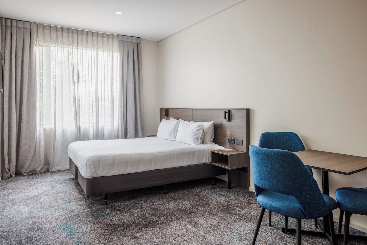 Een hotelkamer met een bed, een bureau en twee stoelen.