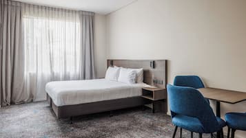 Habitación de hotel con una cama, un escritorio y dos sillas.