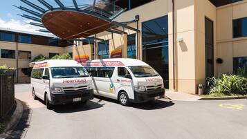 Two Heartland Hotel service vans parked in front of a modern building with large windows and a distinctive roof structure.