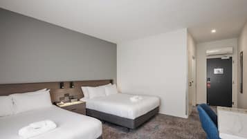 A hotel room with two beds, a desk, and a chair.