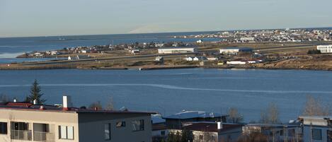 A coastal town with buildings near the water, including a multi-story building with balconies.