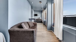 A modern living room with a sofa, a dining area, and a kitchen in the background. - Iceland Comfort Apartments by Heimaleiga (Kópavogur)