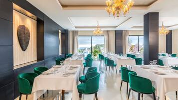 Un restaurante con mesas dispuestas para comer, sillas verdes, candelabros y vistas a la ciudad.