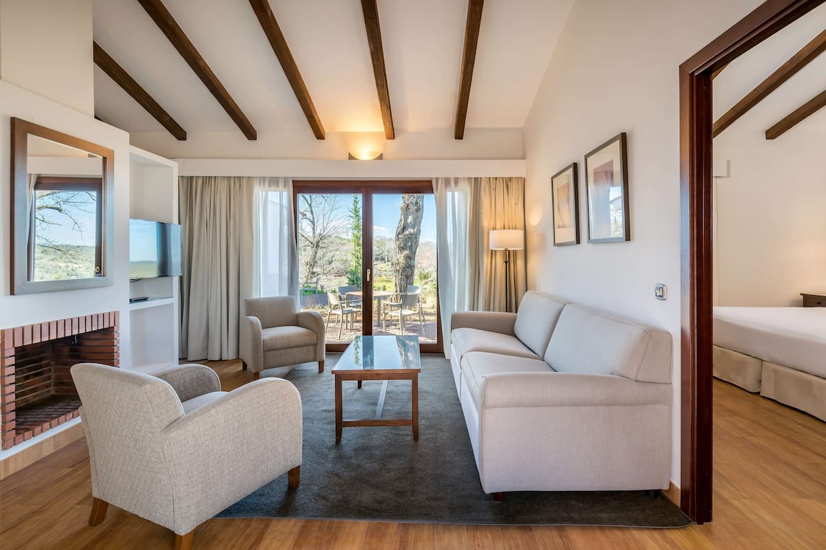 A spacious living room with a fireplace, a sofa, armchairs, a coffee table, and a TV.
