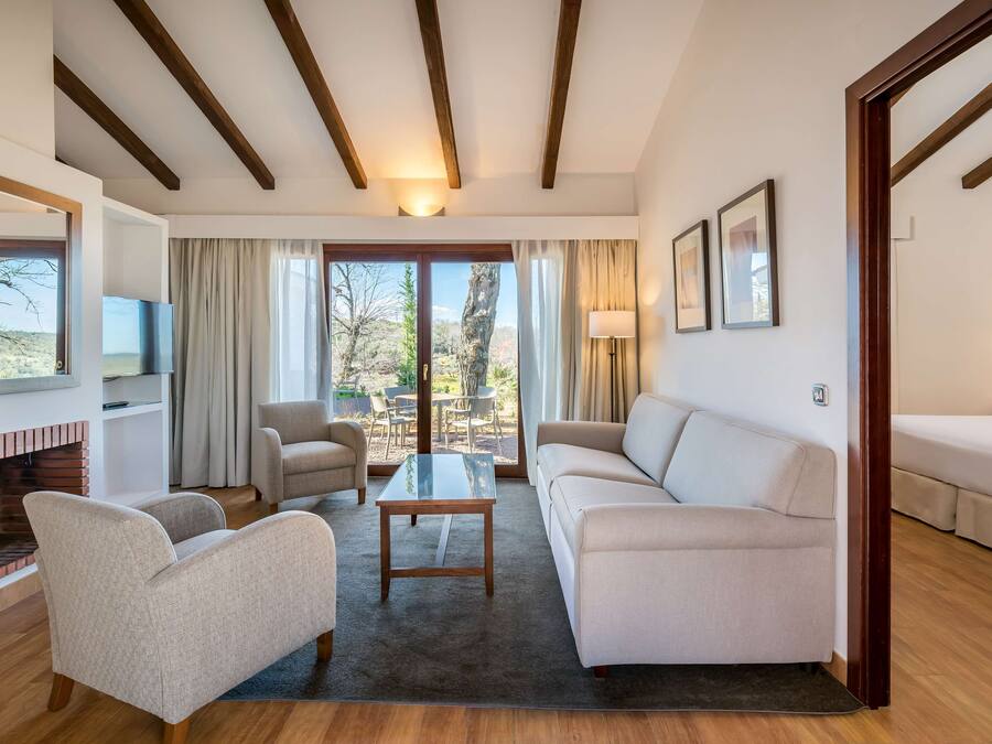 A spacious living room with a fireplace, a sofa, armchairs, a coffee table, and a TV.