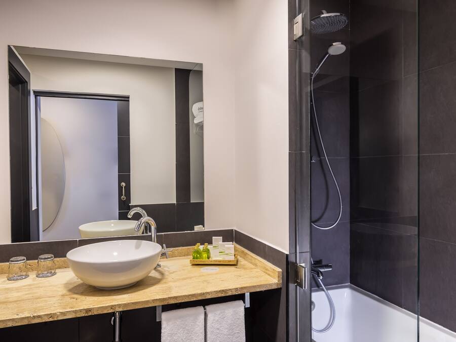 Un baño moderno con un lavamanos grande, espejo y ducha.