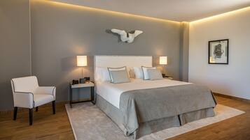 Quarto moderno com cama grande, luminárias de cabeceira, uma cadeira e um aplique.
